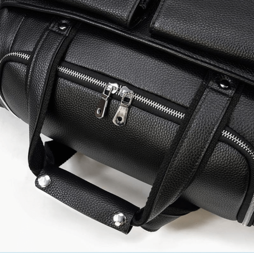 Close-up of a black leather duffle bag showing zippers and handles, perfect for travel and style.