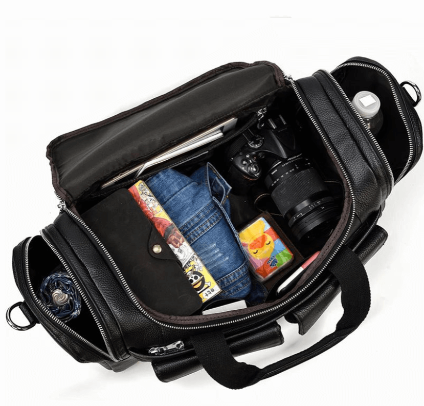 Black leather duffle bag open, showcasing various items including a camera, denim, and water bottle.