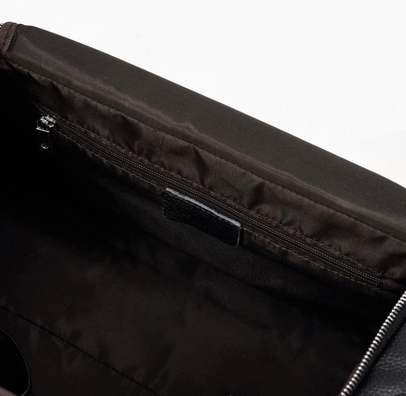 Interiors of a black leather duffle bag, showcasing the spacious compartment with zipper pocket for organized storage.