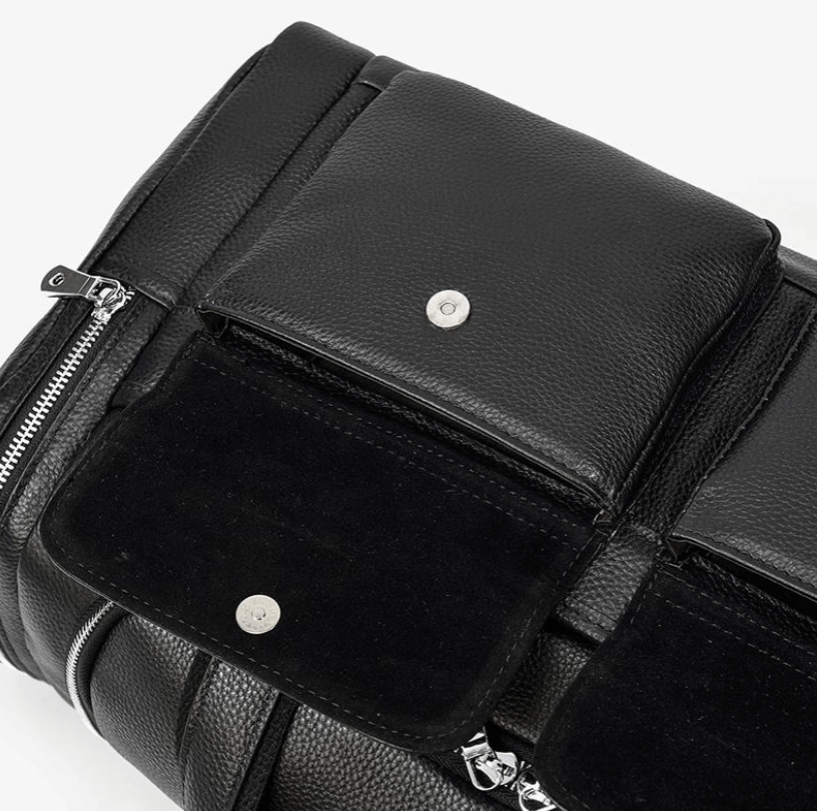 Close-up of black leather duffle bag with snap pockets and zipper detail, ideal for stylish travel or gym use.