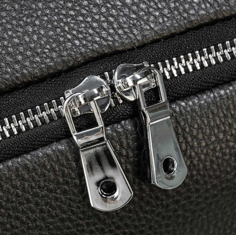 Close-up of dual silver zippers on a black leather duffle bag, showcasing its durable craftsmanship.