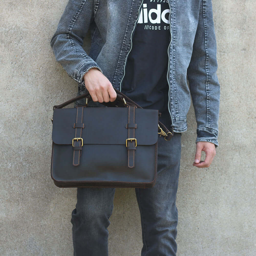 Stylish man holding a dark brown leather courier bag, perfect for everyday use and travel.