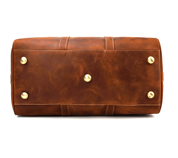 Bottom view of a stylish brown leather duffle bag featuring brass feet, ideal for travel and adventure in the Himalayas.