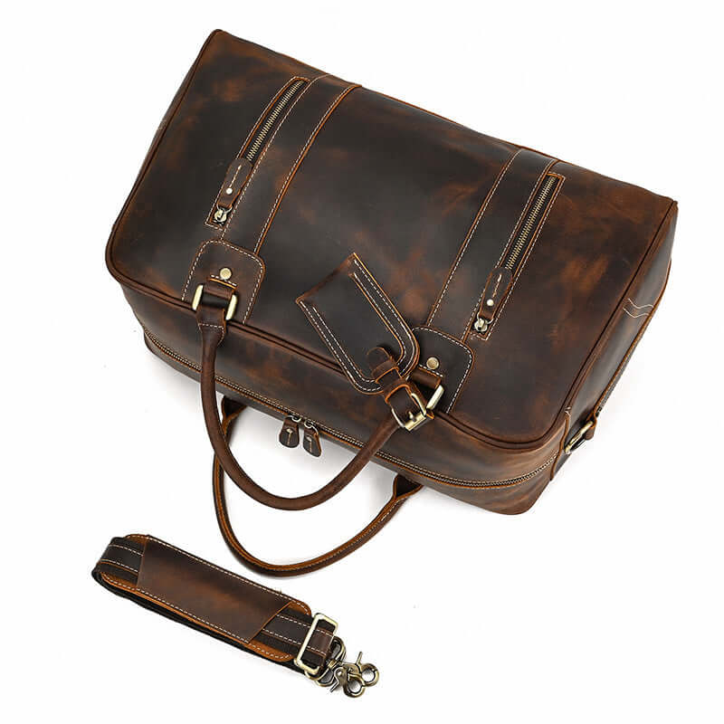 Stylish leather overnight bag in rich brown tones, featuring multiple zippers and detachable strap for easy transport.