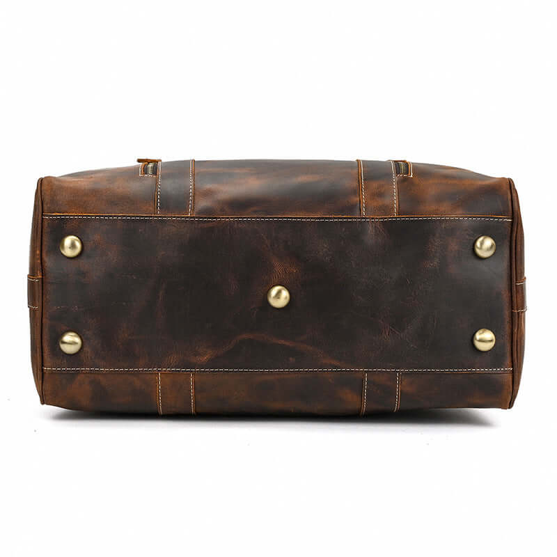 Leather overnight bag base view with brass feet, showcasing durable brown leather craftsmanship.