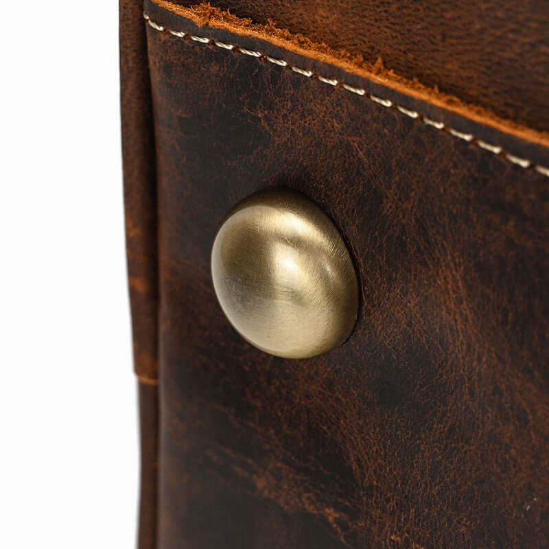 Close-up of a brass button detail on a premium leather overnight bag in rich brown color from the Gobi Desert collection.