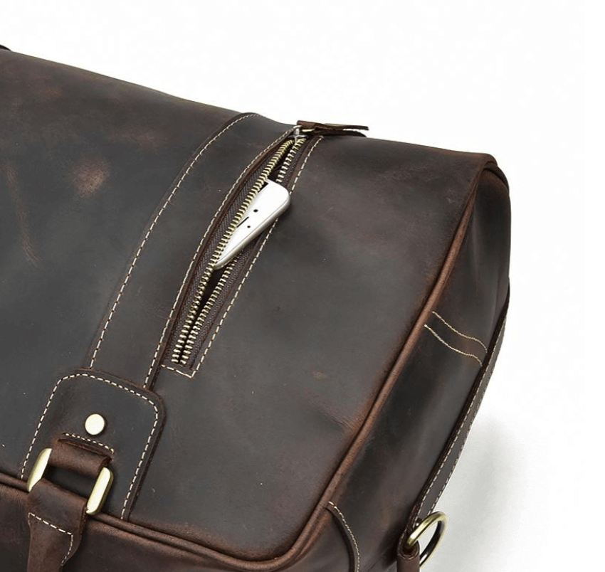 Close-up of a dark brown leather overnight bag with a zipper, showcasing its durable design and premium quality.