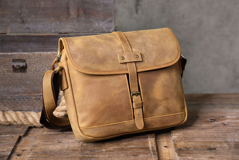 Vintage leather messenger bag in tan color, featuring a buckle strap and stylish design, perfect for everyday use.